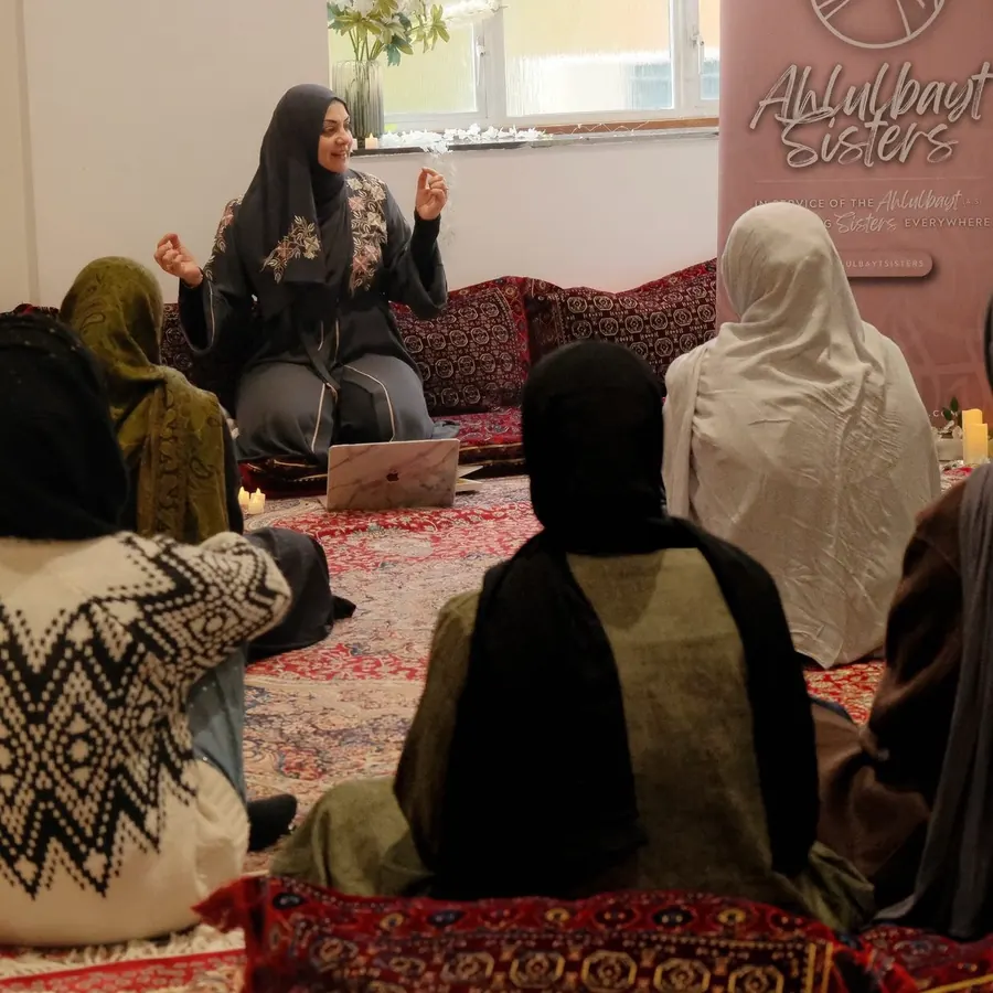 A speaker addressing sisters seated on floor cushions