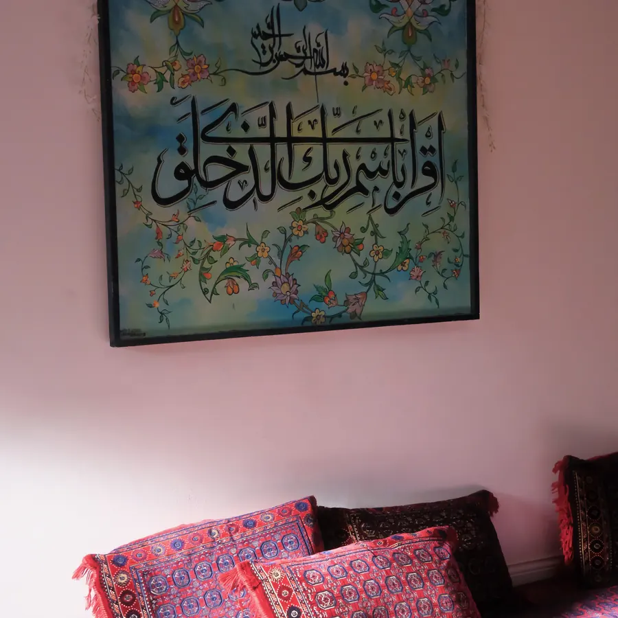 Quranic calligraphy above floor seating at an Ahlulbayt Sisters space